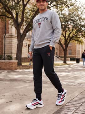 University Pride: A grey Texas Tech logo sweatshirt over slim-fit black joggers and a matching red baseball cap for game-day comfort.