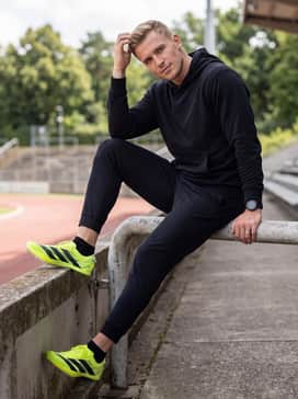 Tapered black athletic warm-up pants and a breathable white performance hoodie to maintain muscle temperature between events.