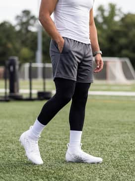 Adizero Impact Ii Football Cleats – A high-intensity training outfit featuring black moisture-wicking compression leggings, charcoal grey mesh athletic shorts, and a fitted white performance tank top.