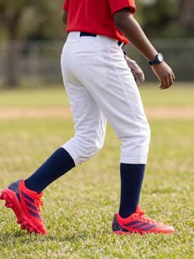 A solid red team jersey tucked into white knicker-style baseball pants, finished with navy blue performance socks and matching red batting gloves for a cohesive team aesthetic.