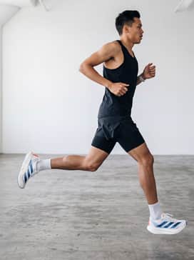 Adizero Prime X Evo Shoes – A sleek, black aerodynamic running singlet paired with matching compression split shorts and ultra-thin white technical socks for a race-ready look.