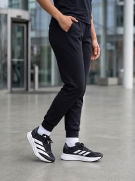 Adizero Sl2 Shoes – A casual streetwear ensemble featuring slim black joggers, an oversized cropped white hoodie, and a sleek nylon crossbody bag for a comfortable weekend errands vibe.