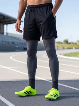 Adizero Sprintstar Shoes – Charcoal grey compression tights worn under black breathable mesh shorts, paired with a fitted long-sleeve tech tee in a moisture-wicking fabric.