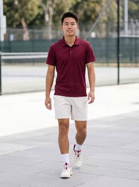 A crisp white performance polo shirt paired with burgundy tennis shorts and white crew socks for a classic, coordinated on-court look.