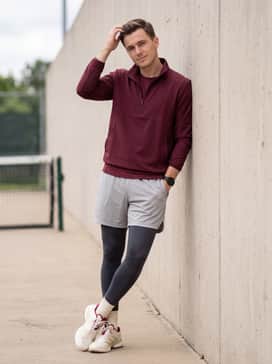 Black athletic training tights layered under light grey ventilated mesh shorts with a matching burgundy quarter-zip track jacket.
