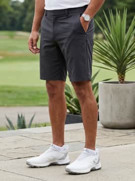 White piqué polo paired with charcoal tech shorts and low-cut white athletic socks for a summer-ready fairway ensemble.