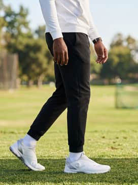 Black tapered athletic joggers and a fitted white compression hoodie for a modern, sporty aesthetic at the driving range.