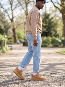 Light wash relaxed-fit jeans with a vintage graphic sweatshirt and a navy blue beanie to lean into a nostalgic 90s-inspired urban style.