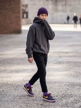A charcoal gray oversized hoodie paired with distressed black skinny jeans and a matching purple beanie for a moody streetwear look.