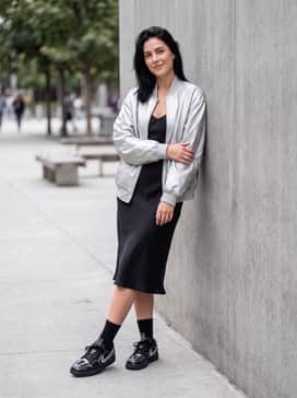 A sleek black midi slip dress layered with an oversized silver bomber jacket for an edgy, high-low evening ensemble.