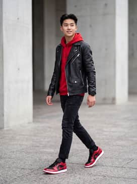 Black slim-fit distressed denim paired with a matching red graphic hoodie and a black leather biker jacket for a bold, edgy urban look.