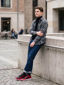 Straight-leg raw indigo jeans cuffed at the bottom, worn with a black turtleneck and a grey flannel overshirt for a sophisticated streetwear aesthetic.