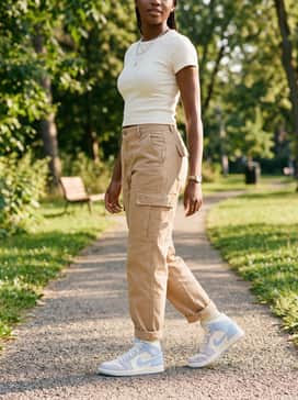 Air Jordan 1 Mid – Loose-fitting tan cargo trousers combined with a fitted white baby tee and silver layered necklaces to lean into a Y2K-inspired streetwear vibe.