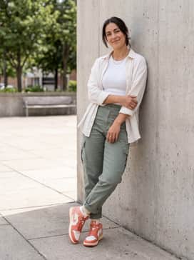 Sage green cargo pants with a fitted white ribbed tank top and minimal gold accessories for a balanced utility-chic ensemble.