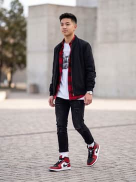 Air Jordan 1 Mid – Distressed black slim-fit jeans paired with a white oversized graphic t-shirt and an unbuttoned red flannel shirt for a classic layered streetwear aesthetic.