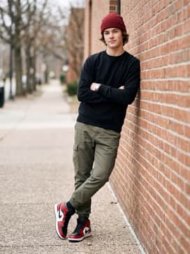 Olive green cargo pants paired with a simple black long-sleeve crewneck and a matching red beanie to coordinate with the shoe's primary hue.