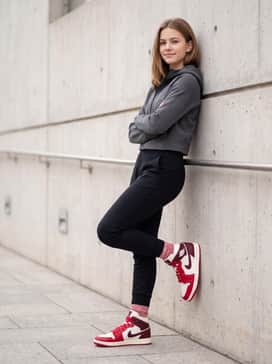 Air Jordan 1 Mid – High-waisted black athletic leggings and a cropped tech-fleece zip-up in a neutral grey, allowing the bold red tones of the shoe to be the focal point.