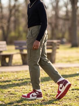 Olive green cargo pants with a tucked-in black turtleneck and a gold chain accessory to lean into a more rugged, urban aesthetic.