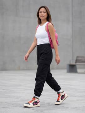 Air Jordan 1 Mid Se Edge – Black high-waisted cargo pants with a cropped white ribbed tank top and a hot pink mini-backpack to coordinate with the glittery swoosh.