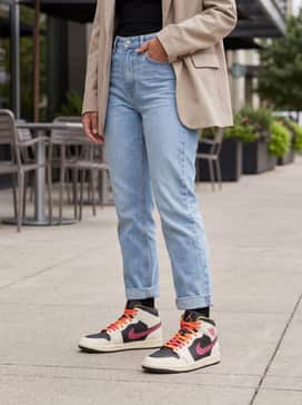A neutral-toned oversized blazer worn over a black mini dress for a sophisticated yet sporty 'high-low' street style look.