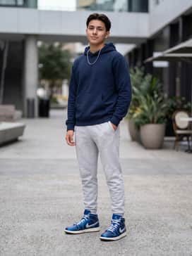 Light grey fleece joggers paired with a navy blue hoodie and a silver chain necklace to complement the metallic accents of the shoe.