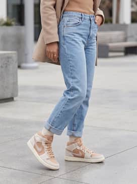 High-waisted light-wash straight-leg denim jeans paired with a tucked-in tan turtleneck and an oversized beige wool coat.