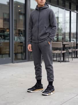 Air Jordan 4 Rm – Style with charcoal grey tapered joggers and a matching tech-fleece hoodie to create a cohesive, athletic-inspired outfit that highlights the gold accents.