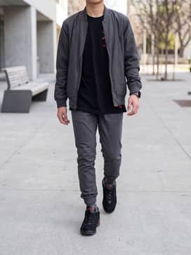 Slim-fit black joggers paired with a classic red-and-black graphic t-shirt and a lightweight grey bomber jacket for a cohesive streetwear look.