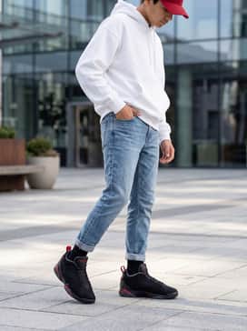 Tapered light-wash denim jeans with a tucked-in oversized white hoodie and a matching red baseball cap to highlight the shoe's accents.