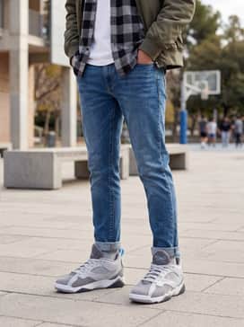 Distressed slim-fit denim jeans worn with a graphic t-shirt featuring vintage basketball imagery and a grey flannel shirt layered open.