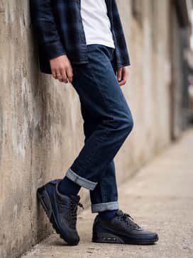 Straight-leg dark wash denim jeans rolled at the cuff, worn with a crisp white t-shirt and an open navy blue flannel shirt.