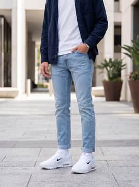 Slim-fit light wash denim jeans with a simple white crewneck t-shirt and an unbuttoned navy flannel shirt for a classic, effortless weekend look.