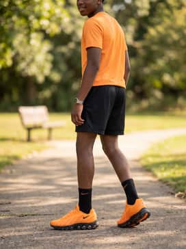 A high-contrast sporty outfit with black athletic shorts, black crew socks, and a matching orange-accented moisture-wicking top.