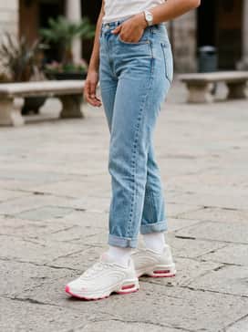 For teens, high-waisted skinny light-blue jeans paired with a cream-colored crop top and a vibrant pink scrunchie to highlight the shoe's accents.