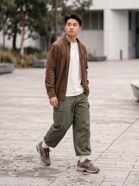Olive green wide-leg cargo pants paired with a heavyweight cream cotton t-shirt and an unbuttoned brown corduroy shirt for a rugged aesthetic.