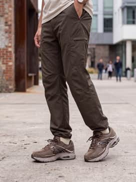 Straight-leg raw denim jeans with a black mock-neck knit sweater and a tan puffer vest for a sophisticated, layered fall look.