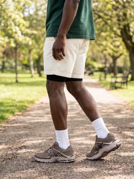 Off-white chino shorts paired with a forest green oversized polo and white crew socks for a clean, retro-sporty weekend outfit.