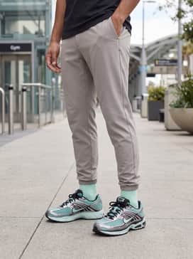 A matching teal-toned workout set with high-waisted leggings and a long-sleeve performance top, layered under an oversized grey puffer vest.