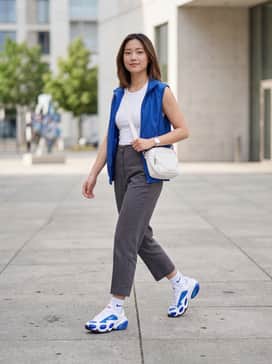 High-waisted cobalt blue joggers paired with a white ribbed crop top and a metallic silver puffer vest for a futuristic street look.