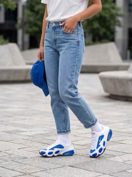Oversized light-wash boyfriend jeans styled with a tucked-in vintage graphic tee and a royal blue baseball cap to match the shoe accents.