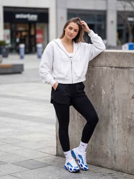 Black high-performance leggings worn with a neon-accented sports bra and an oversized white zip-up hoodie for a seamless gym-to-street transition.