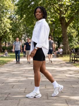 Black cycling shorts worn with a crisp white oversized button-down shirt and silver chunky jewelry for a balanced high-low fashion ensemble.
