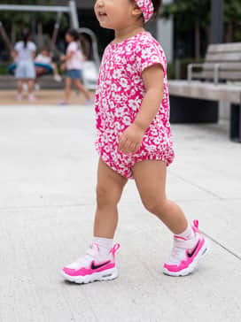A bright pink and white floral cotton romper paired with a soft matching headband for a coordinated summer look.