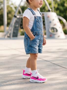 Classic denim overall shorts layered over a simple white ribbed crewneck t-shirt with ruffled white socks.