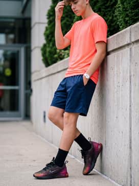 Create a fun, sporty ensemble with navy blue athletic shorts and a neon-colored moisture-wicking top that complements the orange tones in the shoe's gradient.