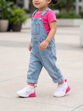 Light wash denim overalls layered over a vibrant pink onesie for a classic, play-ready look that is both durable and stylish.