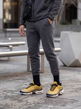 Tapered dark grey joggers combined with a charcoal tech-fleece hoodie and a sleek black crossbody bag for a high-performance aesthetic.