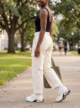 Beige wide-leg cargo pants styled with a fitted black ribbed bodysuit and a silver chain necklace to complement the metallic swoosh detail on the shoes.