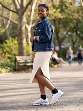 A ribbed white midi dress with a side slit, topped with a vintage-style denim jacket and sleek futuristic sunglasses.