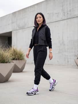 Black tactical cargo pants tucked into white crew socks, paired with a cropped black zip-up hoodie and a reflective tech vest.